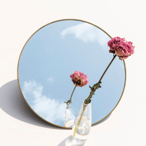 A mirror with reflection of cloud & a rose